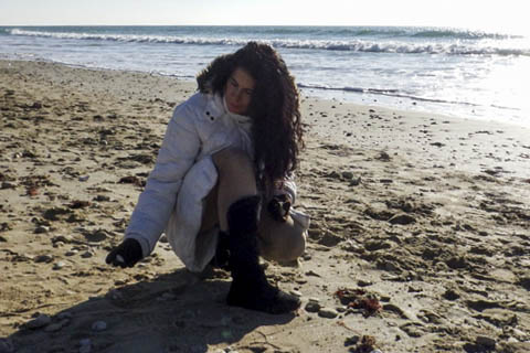 Foto de la artista Mayka Kaíma en la playa buscando piedras en invierno en la playa